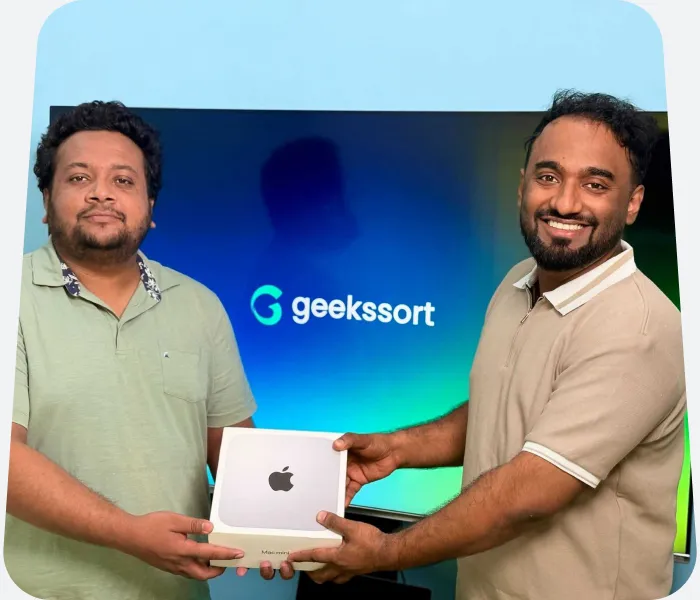 Two Geekssort team members with a new laptop in front of the studio screen