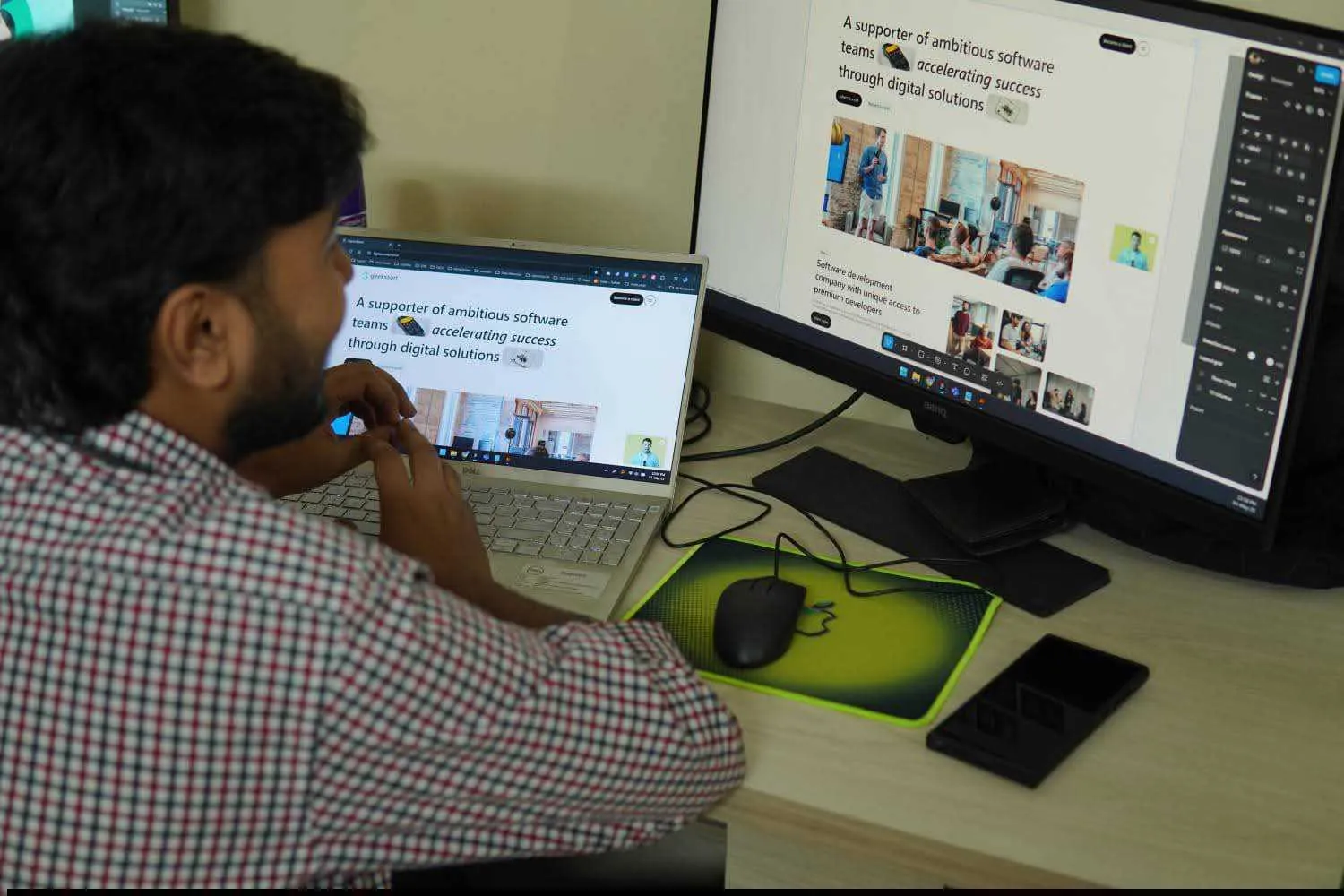 A designer reviewing work on a laptop and a second display.